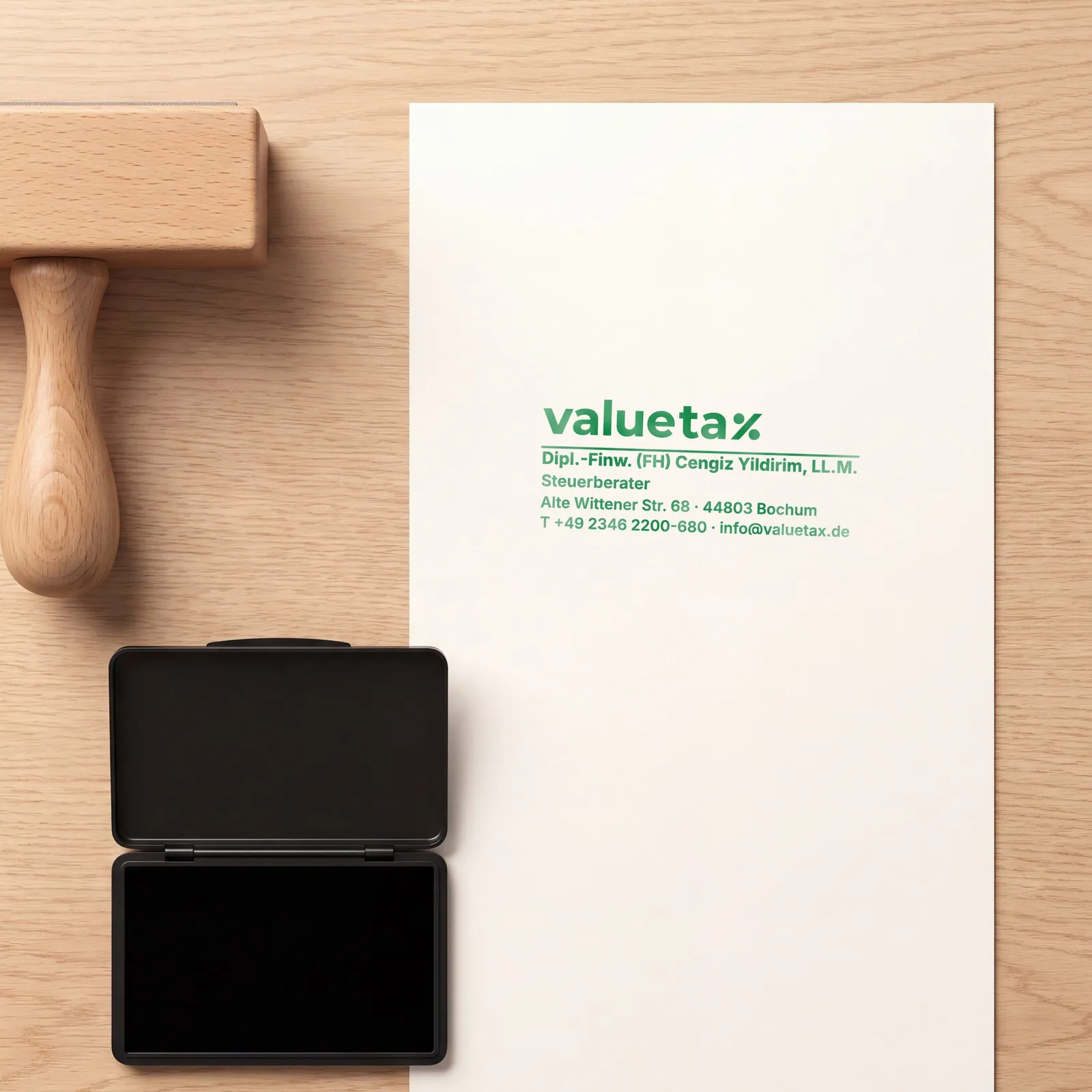 Holzstempel und Stempelkissen neben einem Blatt Papier mit grünem valuetax-Abdruck aus Logo und Kanzleiangaben